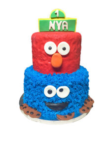 Two-tier Sesame Street birthday cake featuring a red fondant Elmo top tier and a blue buttercream Cookie Monster bottom tier decorated with fondant cookies, made for a first birthday celebration.